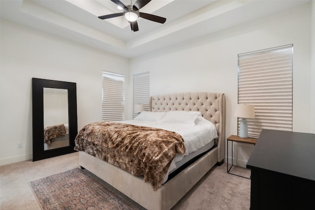 bedroom with a tray ceiling, ceiling fan, and light carpet