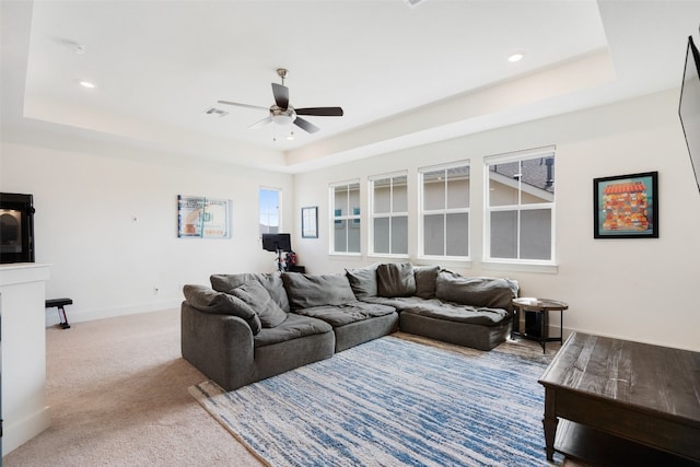 carpeted living room featuring ceiling fan and a tray ceiling