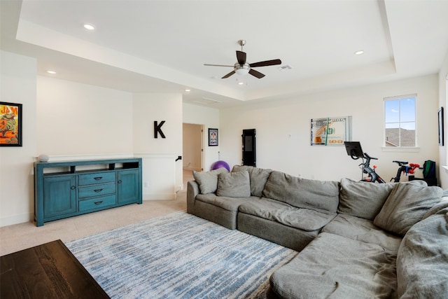 living room featuring a raised ceiling, ceiling fan, and light hardwood / wood-style floors