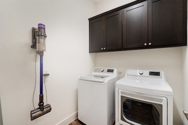 clothes washing area with cabinets and washer and clothes dryer