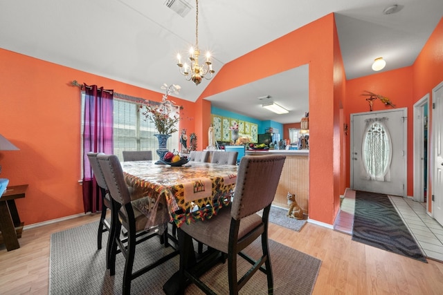 dining space featuring light hardwood / wood-style flooring, vaulted ceiling, and a chandelier