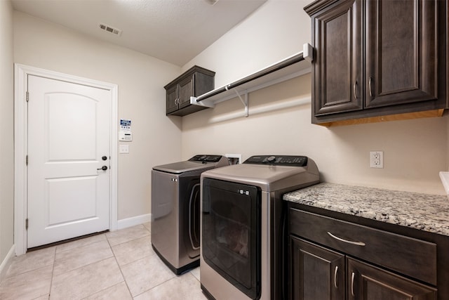 clothes washing area featuring cabinets, washer and dryer, a textured ceiling, and light tile patterned floors