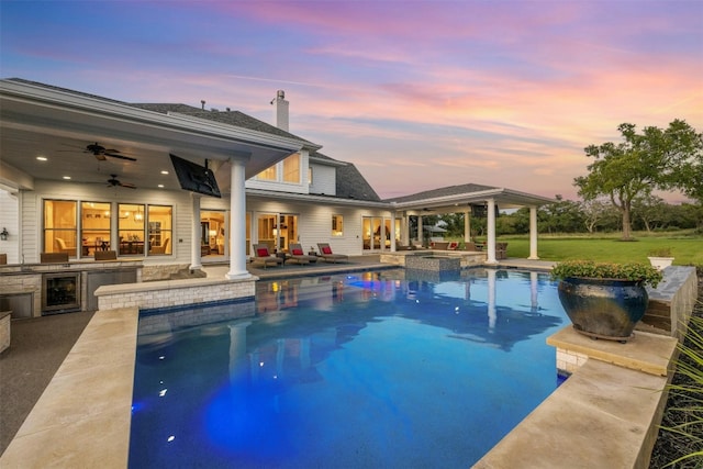 pool at dusk featuring area for grilling, a patio, and ceiling fan