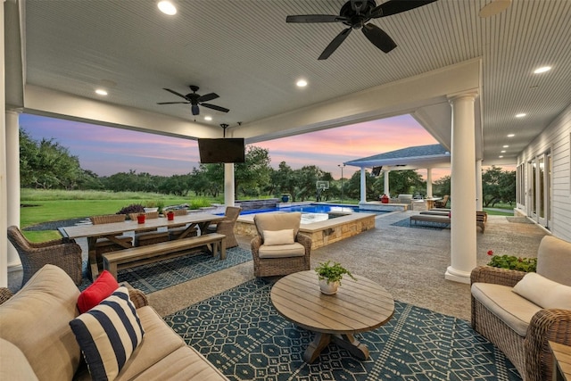 patio terrace at dusk with an outdoor hangout area, ceiling fan, and a swimming pool with hot tub