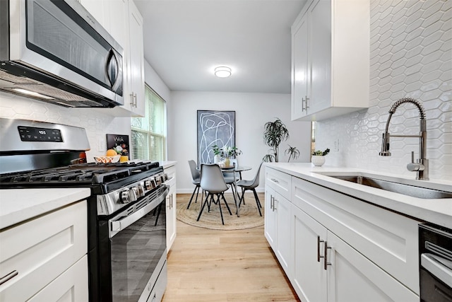 kitchen featuring light wood-type flooring, stainless steel appliances, white cabinetry, and sink