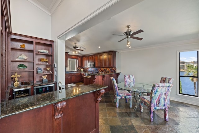 kitchen with ornamental molding, ceiling fan, dark tile patterned flooring, and backsplash