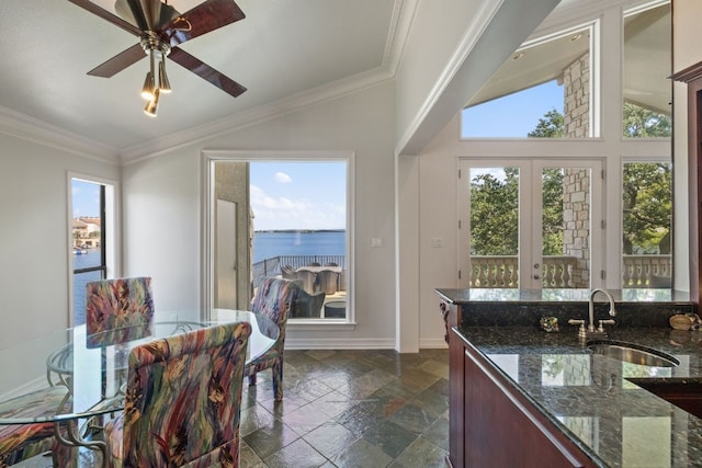 kitchen featuring a water view, ceiling fan, dark tile patterned flooring, sink, and ornamental molding