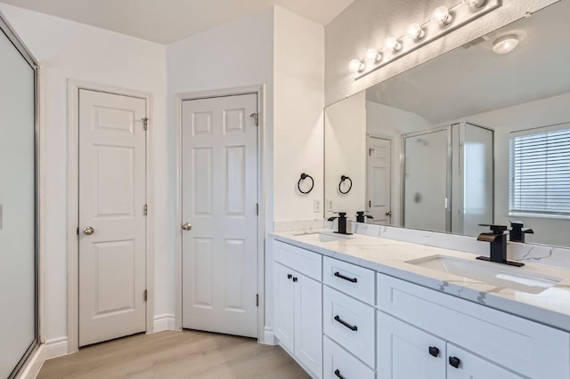 bathroom with vanity, wood-type flooring, and a shower with door