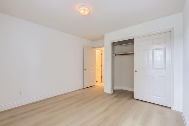 unfurnished bedroom with light wood-type flooring and a closet