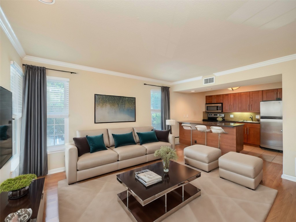 living area with crown molding, visible vents, and a healthy amount of sunlight