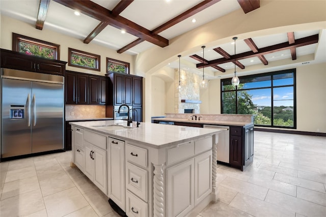 kitchen with white cabinetry, sink, appliances with stainless steel finishes, tasteful backsplash, and an island with sink