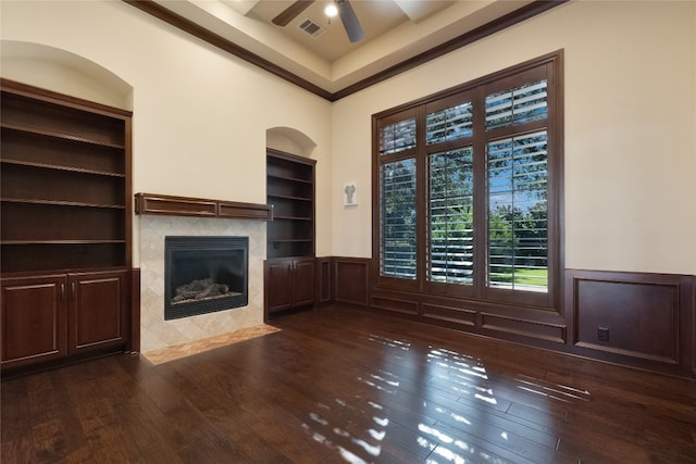 unfurnished living room featuring built in shelves, a towering ceiling, dark hardwood / wood-style floors, ceiling fan, and a fireplace