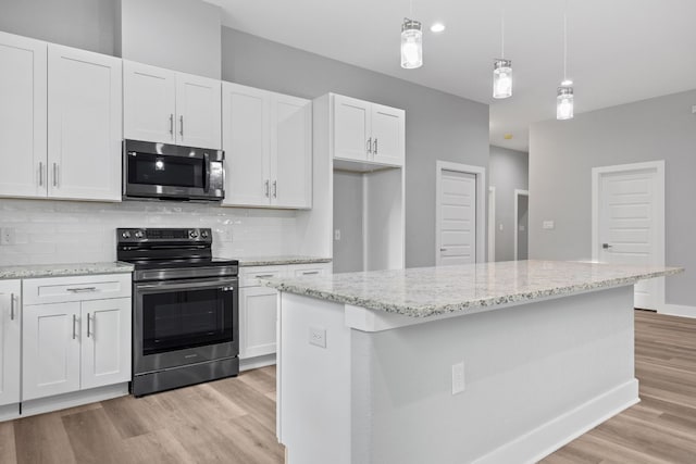 kitchen featuring stainless steel appliances, white cabinetry, a kitchen island, and pendant lighting