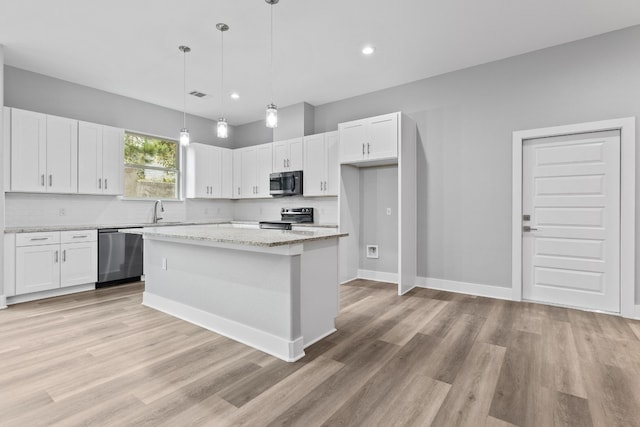 kitchen with a kitchen island, appliances with stainless steel finishes, decorative light fixtures, white cabinetry, and light stone countertops