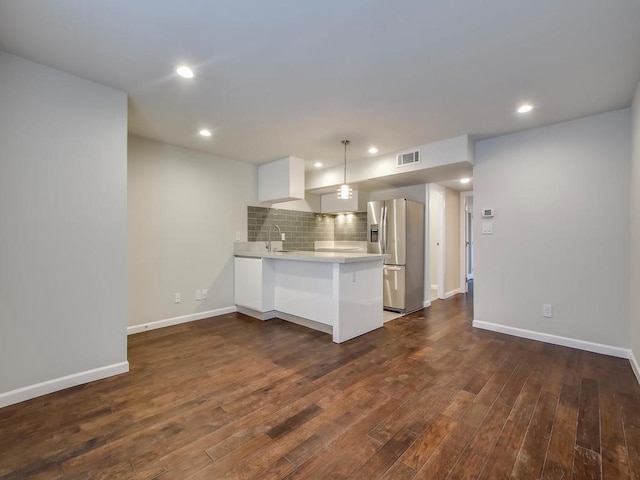 kitchen featuring white cabinetry, sink, stainless steel fridge, decorative backsplash, and kitchen peninsula