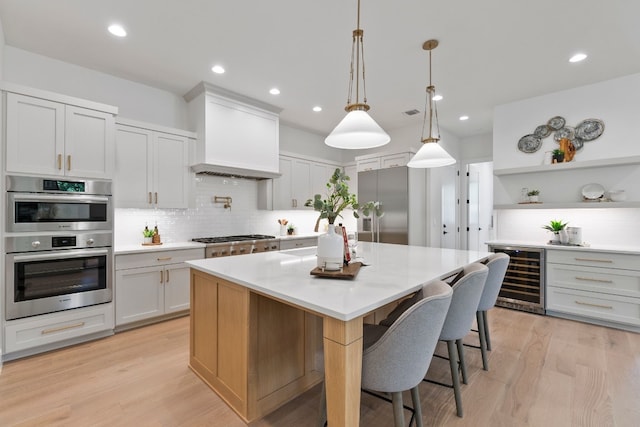 kitchen with white cabinetry, a spacious island, beverage cooler, and hanging light fixtures