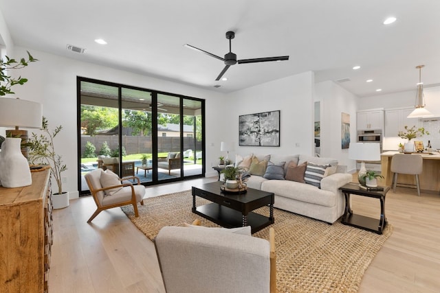 living room with ceiling fan and light hardwood / wood-style flooring