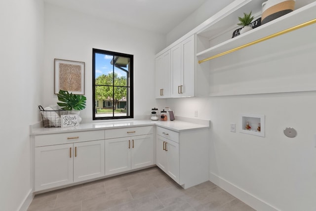 washroom with washer hookup, light tile patterned floors, and cabinets