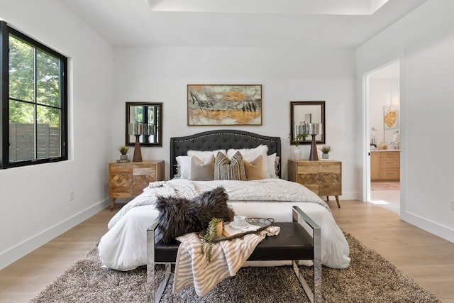 bedroom with ensuite bath and light hardwood / wood-style floors