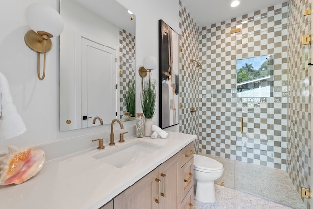 bathroom with tiled shower, vanity, and toilet