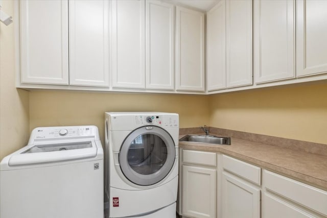 clothes washing area with washing machine and clothes dryer, sink, and cabinets