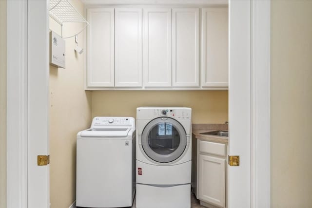 laundry room featuring washing machine and clothes dryer, sink, and cabinets