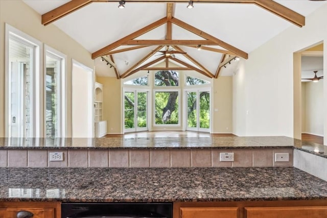 kitchen featuring dark stone counters and lofted ceiling with beams