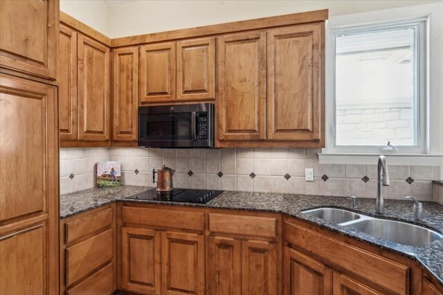 kitchen featuring dark stone counters, black appliances, and backsplash