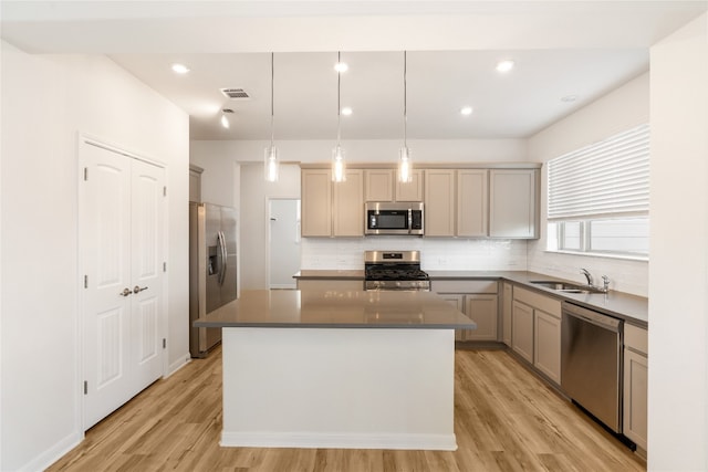 kitchen featuring light wood-type flooring, a center island, stainless steel appliances, sink, and hanging light fixtures