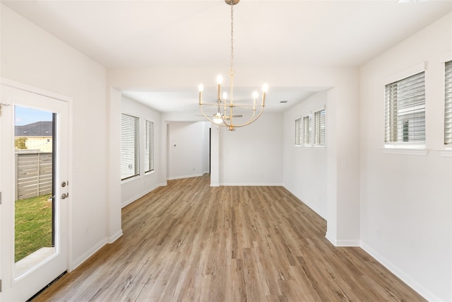 unfurnished dining area featuring light hardwood / wood-style floors, an inviting chandelier, and a wealth of natural light