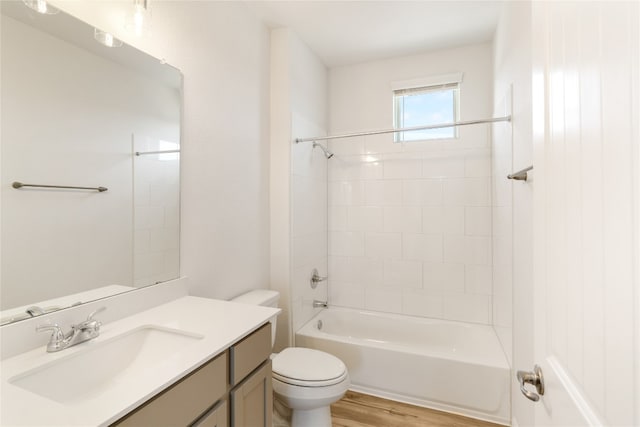 full bathroom with wood-type flooring, tiled shower / bath, vanity, and toilet