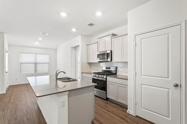 kitchen with sink, stainless steel appliances, tasteful backsplash, dark hardwood / wood-style floors, and a kitchen island with sink