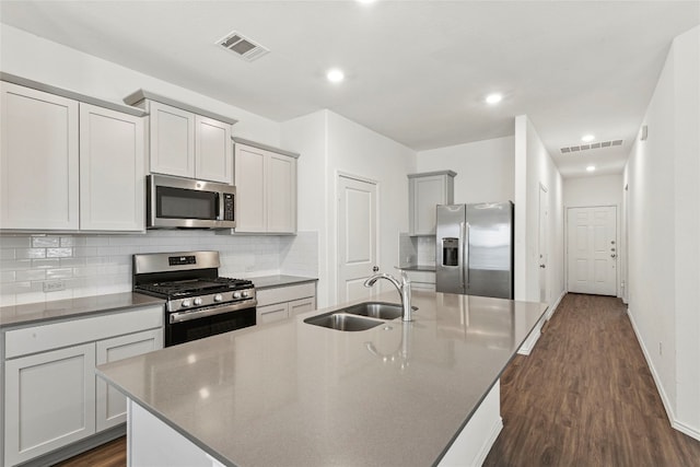 kitchen featuring dark hardwood / wood-style flooring, sink, appliances with stainless steel finishes, and an island with sink