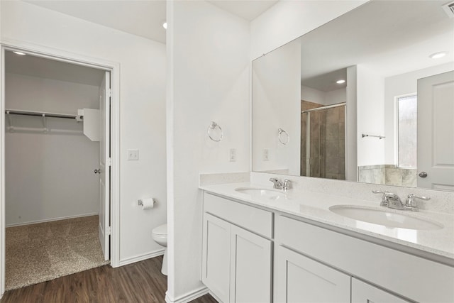 bathroom featuring hardwood / wood-style floors, vanity, toilet, and tiled shower