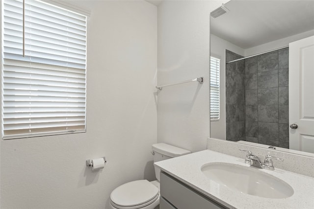 bathroom featuring vanity, toilet, and a tile shower