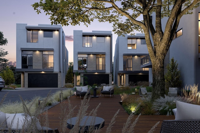 back house at dusk with a garage, outdoor lounge area, and a balcony