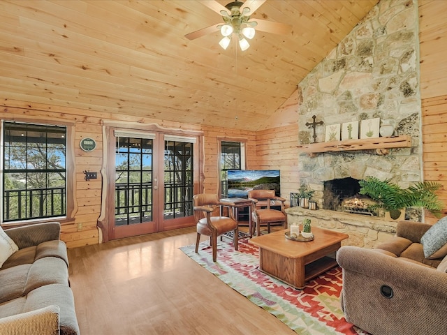 living room with wood walls, wood ceiling, hardwood / wood-style floors, a fireplace, and high vaulted ceiling