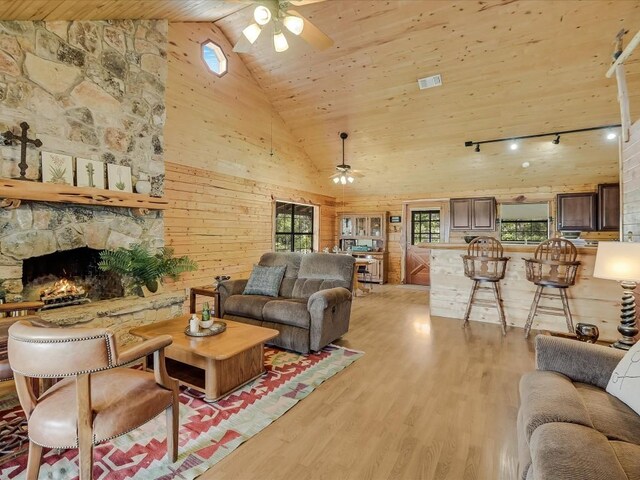 living room featuring ceiling fan, wooden ceiling, wooden walls, and high vaulted ceiling