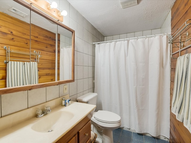 bathroom with tile walls, tile patterned flooring, a textured ceiling, toilet, and vanity