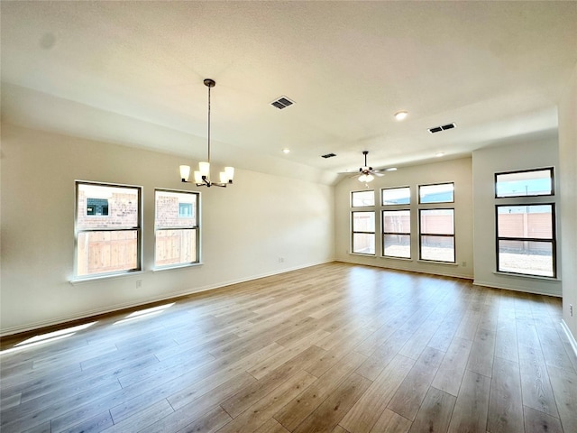 empty room with ceiling fan with notable chandelier and light wood-type flooring