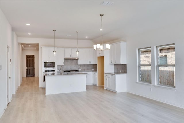 247 Du Bois Ln, Kyle, TX 78640 - kitchen with decorative backsplash, light wood-style floors, white cabinetry, and stainless steel appliances