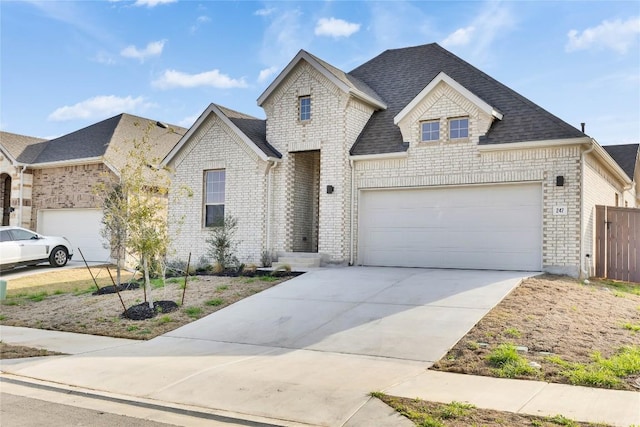 247 Du Bois Ln, Kyle, TX 78640 - french country inspired facade featuring brick siding, a shingled roof, fence, a garage, and driveway