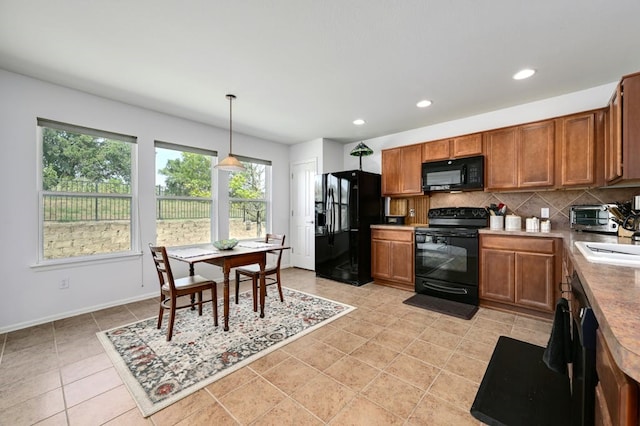 kitchen featuring decorative light fixtures, backsplash, black appliances, and plenty of natural light