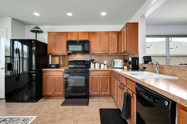 kitchen with decorative backsplash, sink, black appliances, and light tile patterned floors