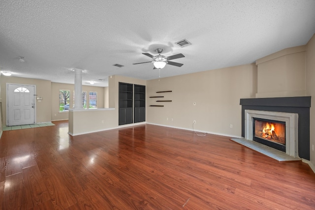 unfurnished living room featuring decorative columns, hardwood / wood-style flooring, ceiling fan, and a textured ceiling