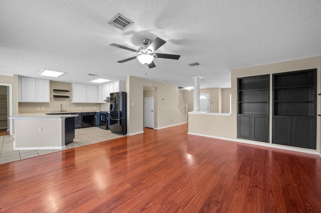 unfurnished living room featuring ceiling fan, a textured ceiling, light wood-type flooring, and sink