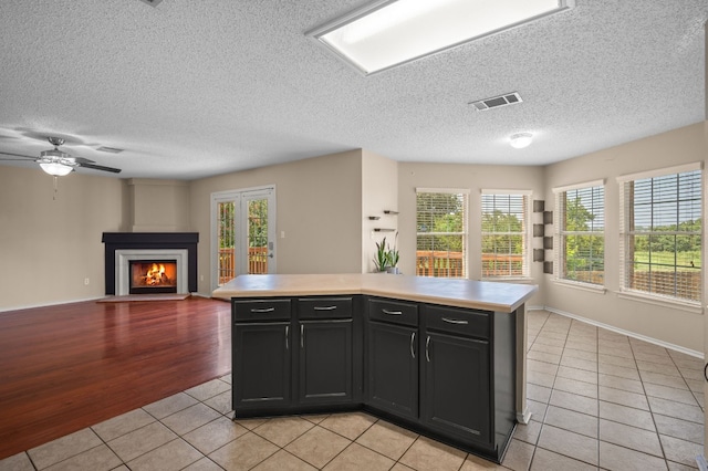 kitchen featuring ceiling fan, a textured ceiling, light hardwood / wood-style floors, and a kitchen island