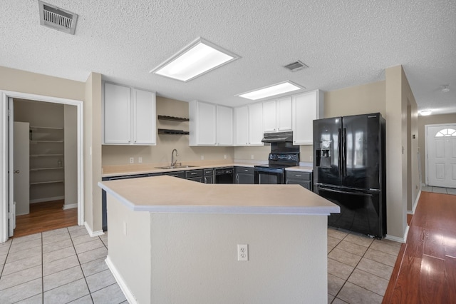 kitchen with a kitchen island, black appliances, sink, light hardwood / wood-style floors, and white cabinetry