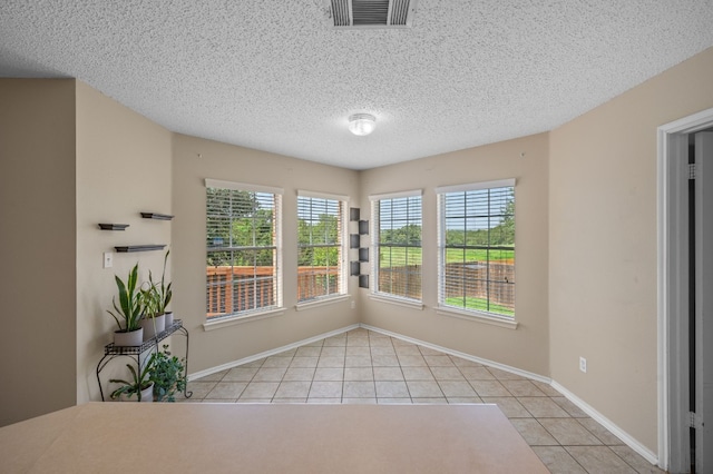 unfurnished dining area featuring light tile patterned flooring and a textured ceiling