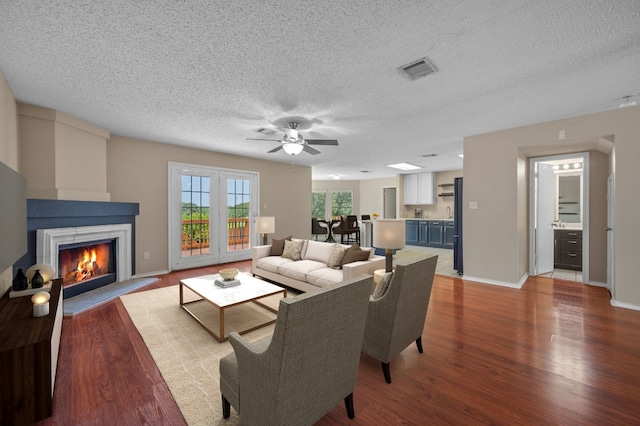 living room with ceiling fan, a textured ceiling, and light wood-type flooring